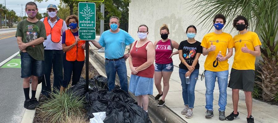 member of Downtown Rotary Club around Adopt-A-Street sign after a cleanup