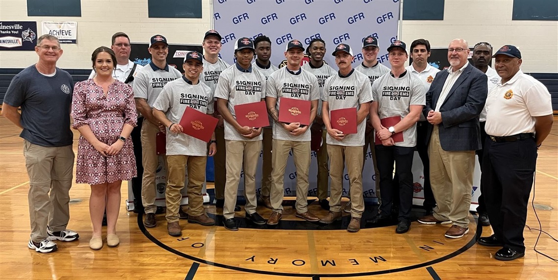 Gainesville City Commissioner Ed Book (far left), Mayor Harvey Ward (third from right) and GFR leaders stand with the 2023 candidates following the signing ceremony.