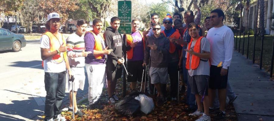 Sigma Lambda Beta members posing under Adopt-A-Street sign