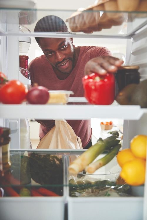 guy arranging food in a refrigerator