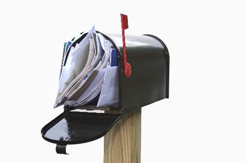 mailbox on a post overflowing with junk mail inside it