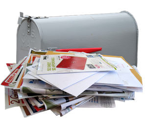 stack of junk mail in front of a metal mailbox