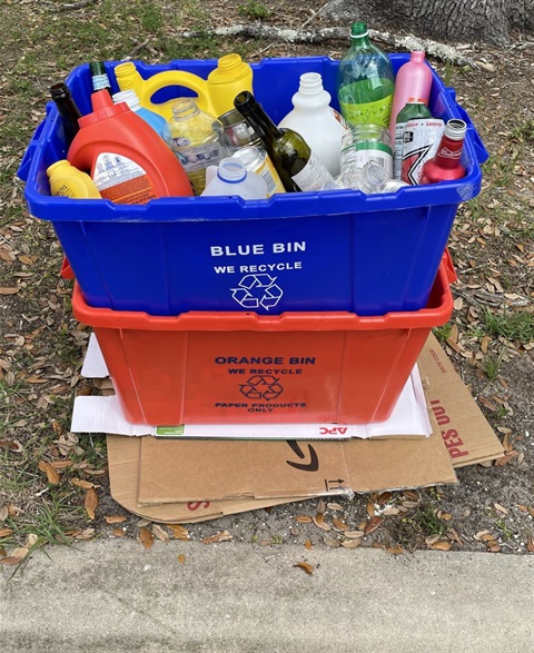 blue recycle bin on top of orange recycle bin set curbside for collection