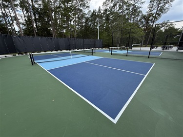 Two adjacent outdoor blue pickleball courts.